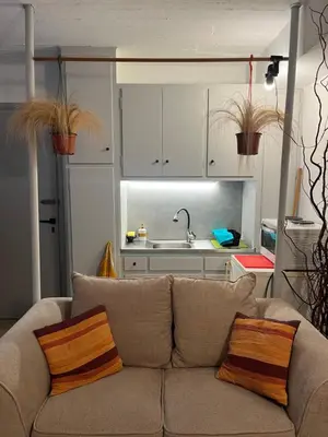 a living room with a couch and a kitchen at Cozy quiet studio near the sea in Athens