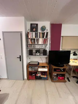 a living room with a television and a book shelf at Cozy quiet studio near the sea in Athens