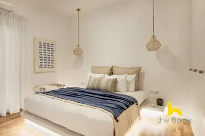 a bedroom with a large bed and two pendant lights at Marina View Haven - King Beds and Cosy Fireplace in Piraeus