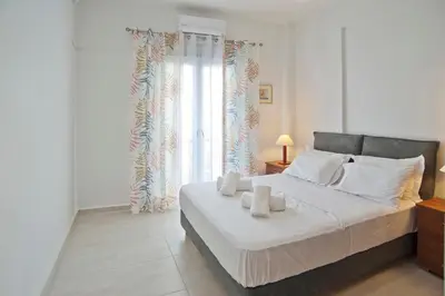 a bedroom with a bed and a large window at SeaLiv Apartment by LobbySquare in Piraeus