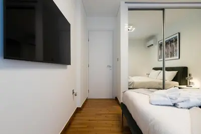 a bedroom with two beds and a flat screen tv at Bright and Stylish Apartment in Palaio faliro in Athens