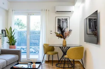 a living room with a table and chairs and a couch at Bright and Stylish Apartment in Palaio faliro in Athens