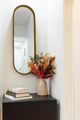 a vase with flowers on a table with a mirror at Bright and Stylish Apartment in Palaio faliro in Athens
