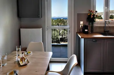 a kitchen with a table and chairs and a window at Thenia's Bellevue apartment in Saronida