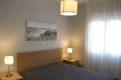 a bedroom with a bed and two lamps and a window at Thenia's Bellevue apartment in Saronida