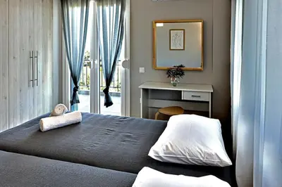 a bedroom with a bed and a table and a mirror at Thenia's Bellevue apartment in Saronida