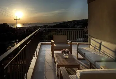 a balcony with a couch and a chair and a table at Thenia's Bellevue apartment in Saronida