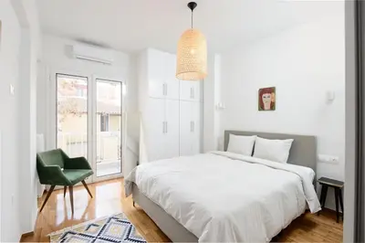 a bedroom with a white bed and a green chair at Zen Spring, Neapoli in Athens