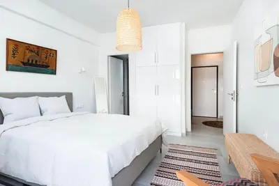 a white bedroom with a white bed and a table at Zen Spring, Neapoli in Athens