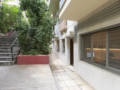 an empty sidewalk next to a building with a tree at Chic and modern apartment in the center of Kolonaki in Athens