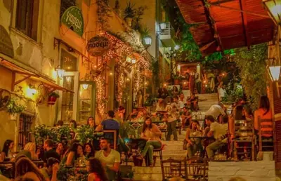 a group of people sitting at tables in a street at Home 7 Minutes Away From Stavros Niarhos in Athens
