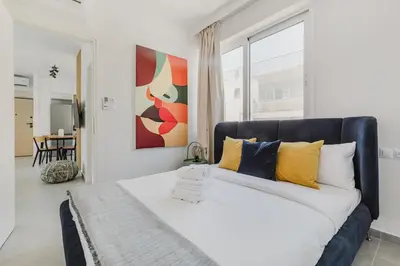 a bedroom with a large bed with yellow and blue pillows at A Place 4U 20, 2 Bedrooms & 2 Bathrooms with view of Acropolis in Athens