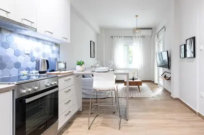 a kitchen with white cabinets and a table with a chair at Zeus 1 bdr apartment in Koukaki in Athens