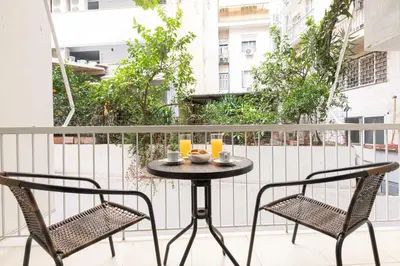 a table on a balcony with two chairs and orange juice at Zeus 1 bdr apartment in Koukaki in Athens