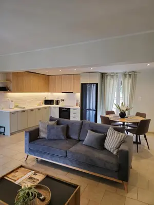 a living room with a blue couch and a kitchen at Tranquil 2BR Penthouse Petralona in Athens