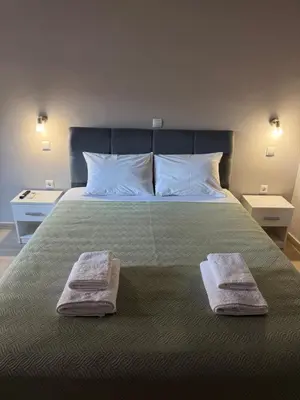 a bedroom with a large bed with two towels on it at FlyHome Apartments near the Airport in Spáta