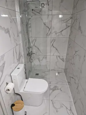 a white bathroom with a toilet and a shower at FlyHome Apartments near the Airport in Spáta