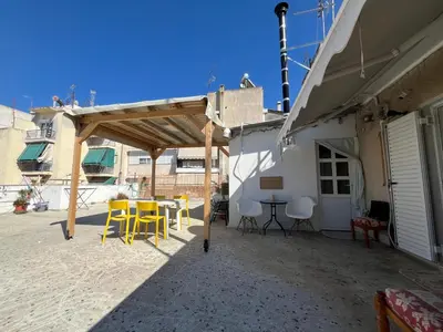 a patio with yellow chairs and a table and a building at For big family in Athens