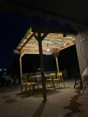 a table and chairs under an umbrella at night at For big family in Athens