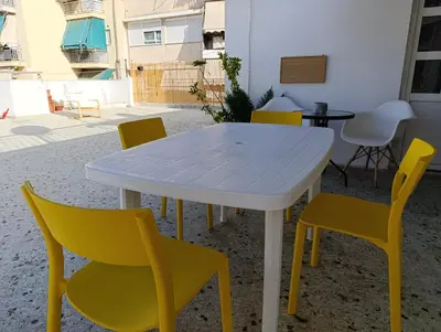 a white table and yellow chairs on a patio at For big family in Athens