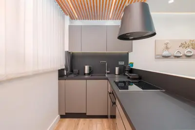 a kitchen with white cabinets and a black counter top at Modern Urban Oasis with Private Plunge Pool in Piraeus