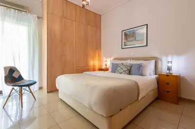 a bedroom with a large bed and a chair at Phaedrus Living Moschato City Flat in Piraeus