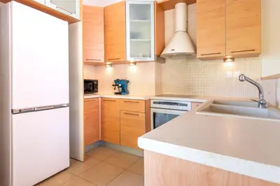 a kitchen with wooden cabinets and a white refrigerator at Phaedrus Living Moschato City Flat in Piraeus