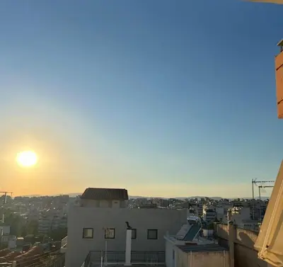 a view of a city with the sun setting behind a building at Modern and comfortable apartment 5km from center in Athens