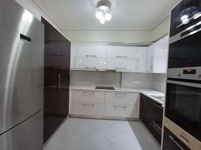 a kitchen with white cabinets and a black appliance at Modern and comfortable apartment 5km from center in Athens