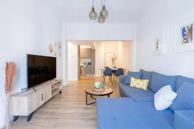 a living room with a blue couch and a tv at Urban Comfort 2 bdrm next to Metro in Athens