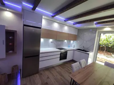 a kitchen with white cabinets and a table with a wooden floor at Island 3siblings in Athens