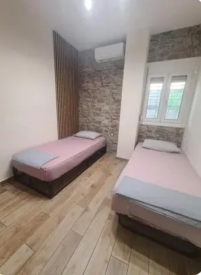 two beds in a room with wooden floors and windows at Island 3siblings in Athens
