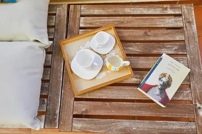 a tray with two cups and a book on a table at soft blue apartment near seaside in Porto Rafti
