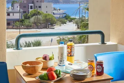 a table with fruits and bottles on a balcony with a view at soft blue apartment near seaside in Porto Rafti