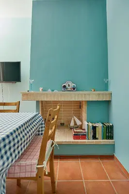 a room with a table and a chair and a shelf with books at soft blue apartment near seaside in Porto Rafti