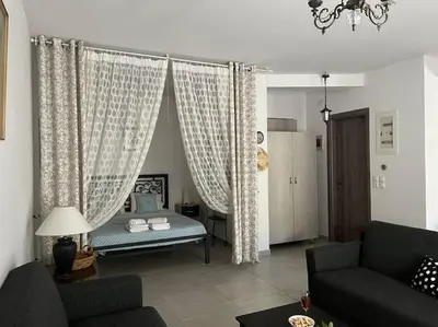 a living room with curtains and a couch at Aurora Studio Lagonissi in Lagonissi