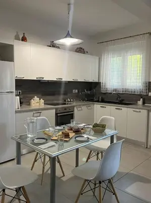 a kitchen with a table with chairs and a refrigerator at Aurora Studio Lagonissi in Lagonissi