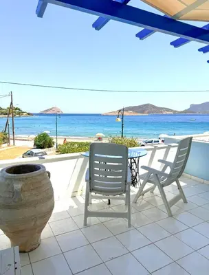 a patio with two chairs and a table and the ocean at Aegean Pearl in Porto Rafti
