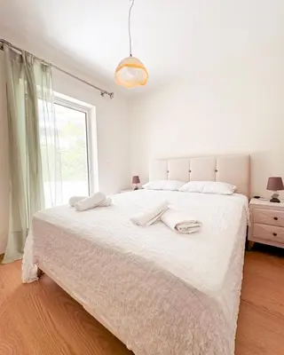 a white bedroom with a large bed with two towels on it at Aegean Pearl in Porto Rafti