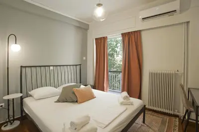 a bedroom with a bed with white sheets and a window at Hill House Lycabettus Stylish near Athens Center in Athens