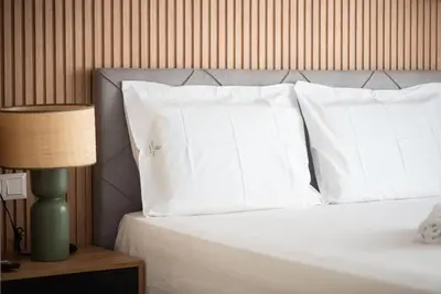 a bed with white pillows and a table with a lamp at Stylish Comfort Apt in Athens Centre in Athens