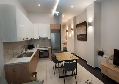 a kitchen with white cabinets and a wooden table at Sia's Retreat 1 Modern Apt Athens Riviera in Athens