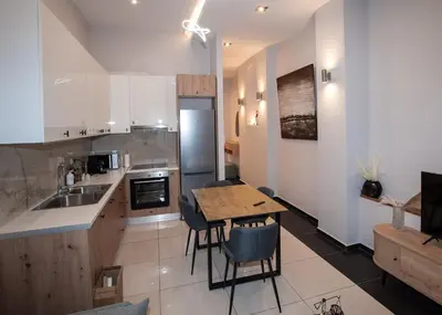 a kitchen with a table and a kitchen with white cabinets at Sia's Retreat 1 Modern Apt Athens Riviera in Athens