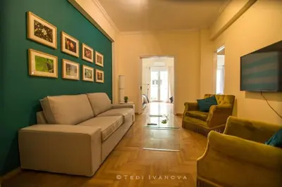 a living room with a couch and a green wall at Unique 3 BDRM apartment, 5 min walk from Acropolis in Athens