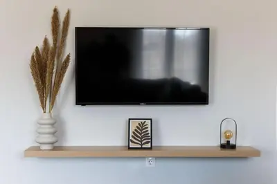a flat screen tv on a wall with a shelf at Modern Top Floor Apt, 5min to Acropolis & Plaka in Athens