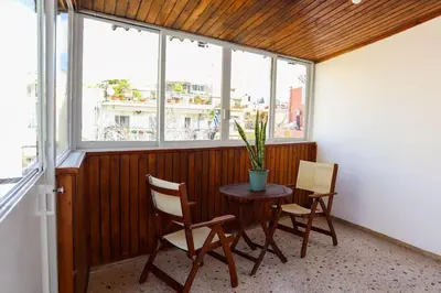 a table and chairs in a room with windows at Modern Top Floor Apt, 5min to Acropolis & Plaka in Athens