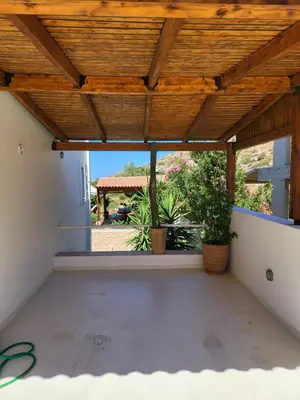 a patio with a wooden roof with potted plants at Villa Solaris in Sounio