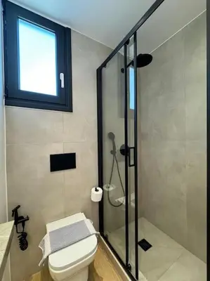 a bathroom with a shower and a toilet and a window at BlueMotion - PortSuite 5B in Piraeus