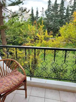 a balcony with a chair and a view of a garden at Sunny studio near metro in Athens