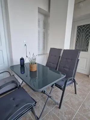 a glass table and two chairs in a room at Stone Apartment Close to the Airport in Spáta